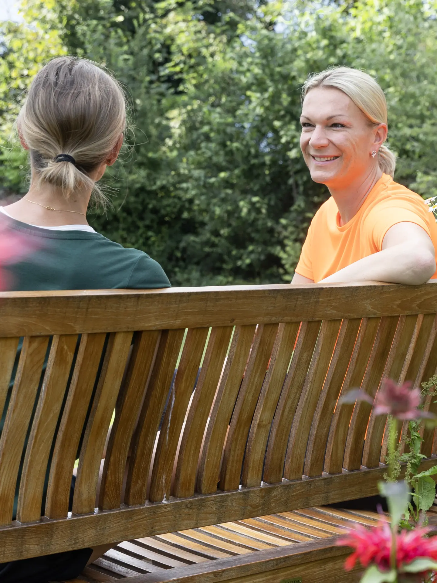 Maria Höfl-Riesch im Gespräch mit einer Teilnehmerin auf einer Parkbank im Garten des Park Igls