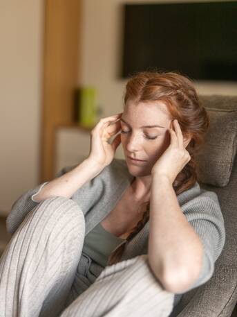 Nachdenkliche Frau mit langen roten Haaren – Moment der Selbstreflexion im Park Igls Medical Spa Resort
