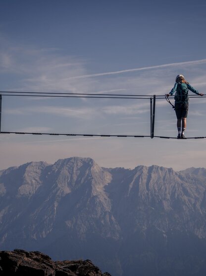 Person auf Hängebrücke vor Bergpanorama am Glungezer Klettersteig