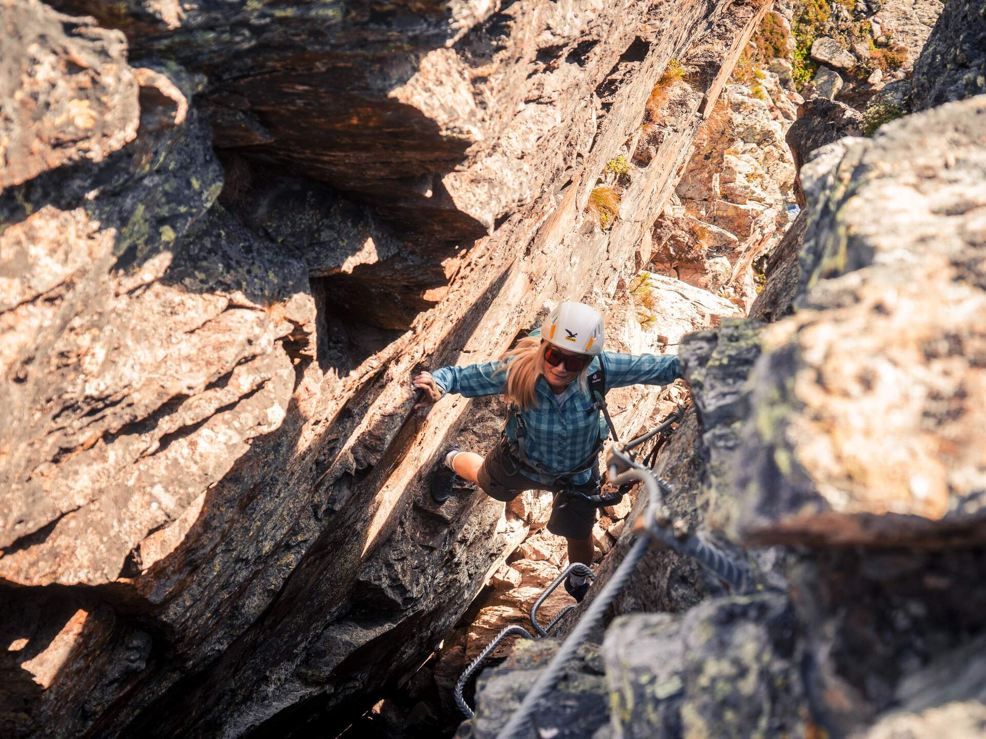 Kletterin im Sagen-Klettersteig am Glungezer zwischen Felsen mit Stahlseil und Trittstufen | © Tourismusverband Hall-Wattens