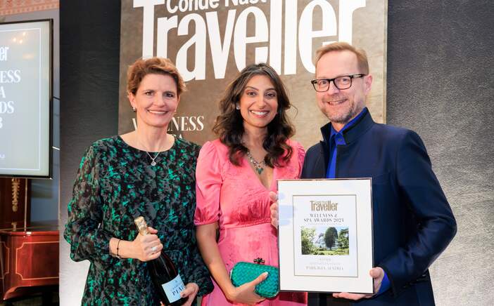 Drei Personen präsentieren stolz eine Auszeichnung vor einem Condé Nast Traveller Banner