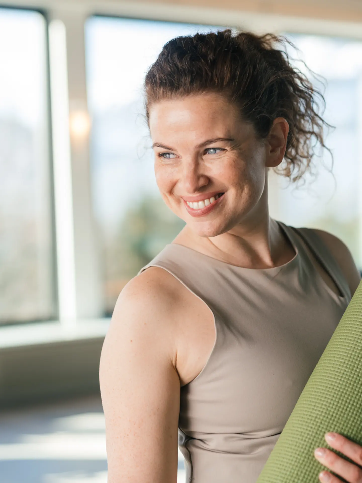 Lachende Frau mit Yogamatte