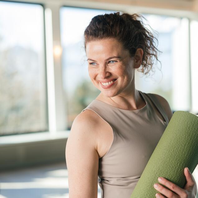 Lachende Frau mit Yogamatte