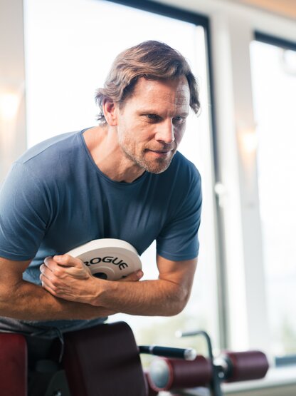 Mann trainiert Bauchmuskeln im Fitnessstudio mit Gewichtsscheibe