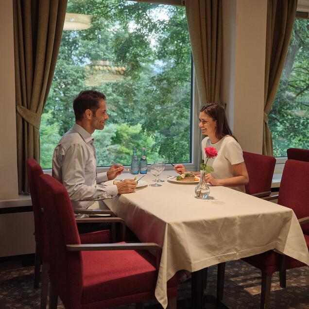 Paar isst an gedecktem Tisch vor Fenster mit Blick ins Grüne