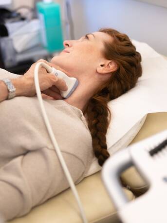 Frau bei einer Ultraschalluntersuchung der Halsschlagader in Rückenlage