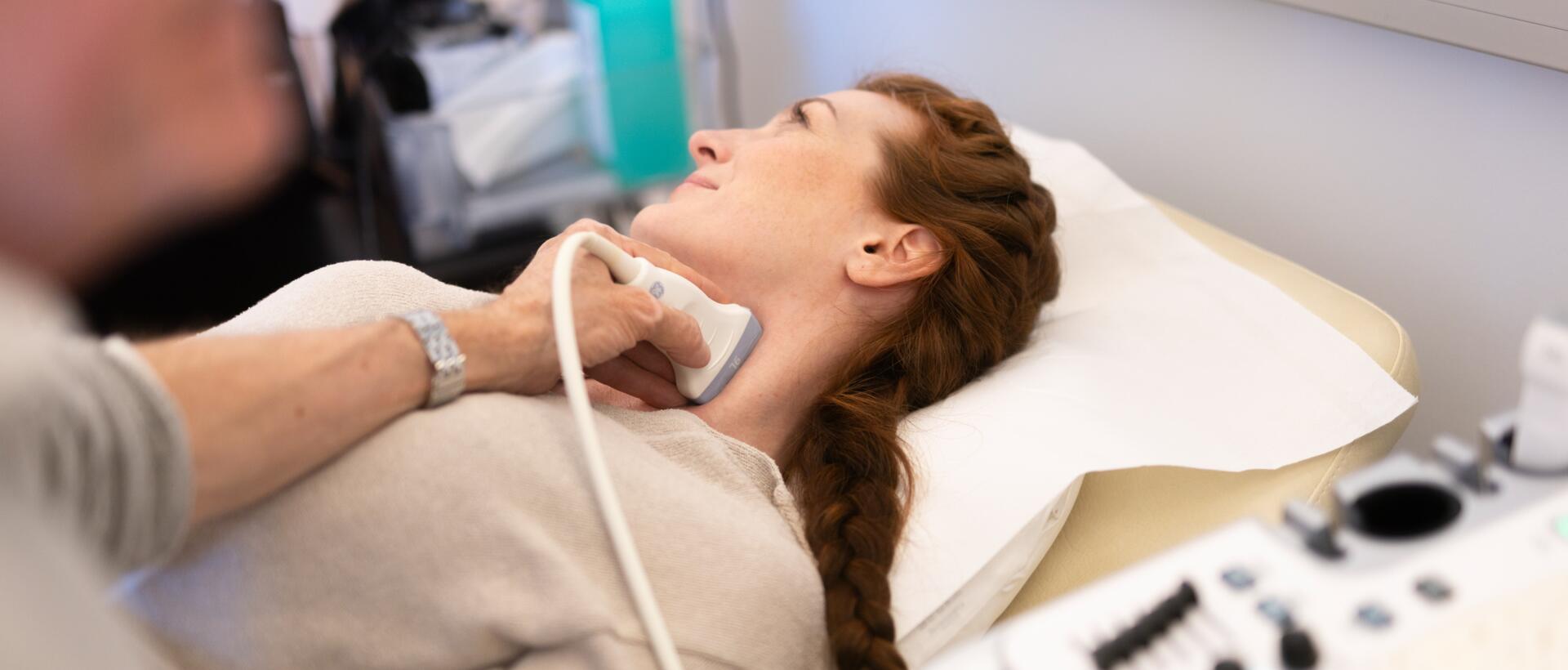 Frau bei einer Ultraschalluntersuchung der Halsschlagader in Rückenlage