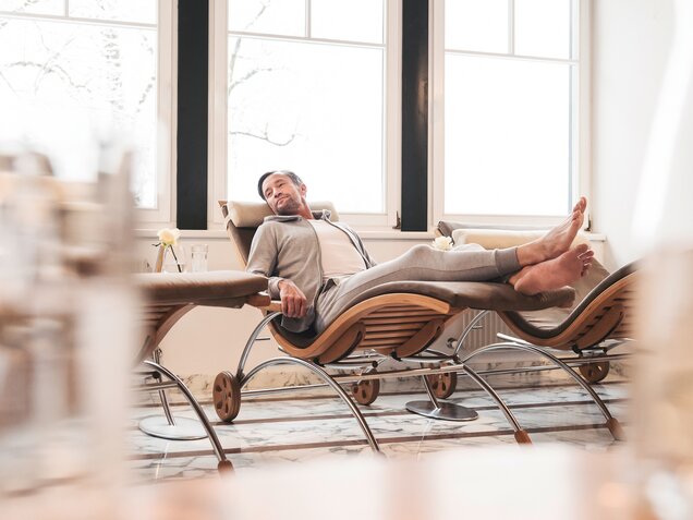 Mann entspannt in Liege im Spa vor Fenster
