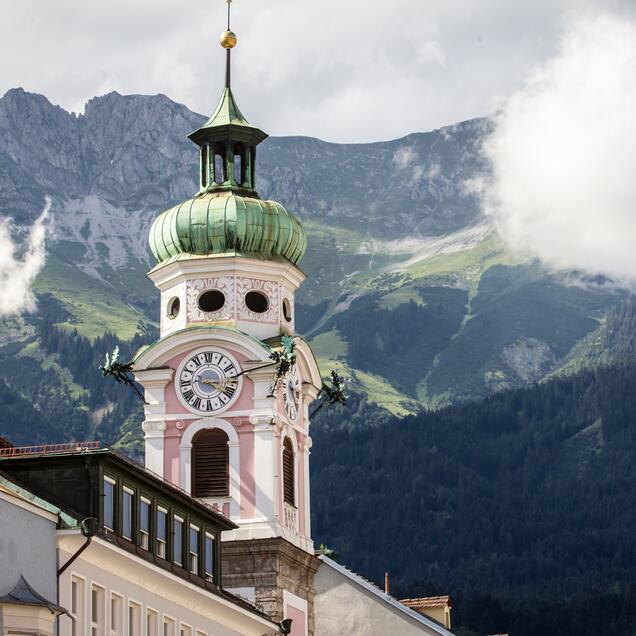 Die Innsbrucker Spitalskirche ragt vor einer Bergkulisse empor | © Tirol Werbung / Erwin Haiden